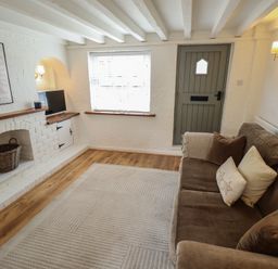 A living room with a couch and television at Pax Cottage