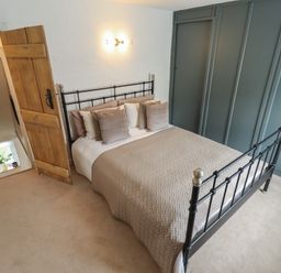 A bedroom with a bed and a wooden door at Pax Cottage