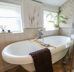 A bathtub with a towel and decorative items at Pax Cottage