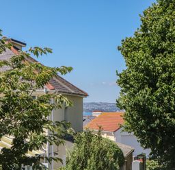 A view of houses and trees with sea in the background at 3 Heath Park Brixham