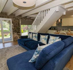 A living room with a sofa and kitchen area at The Cart House in Pontsian