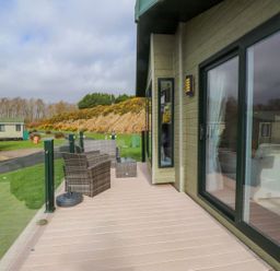 A deck area with chairs and a table at 56 The Stables Pwllheli