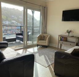 A living room with a TV and balcony view at Rivercrest in Looe