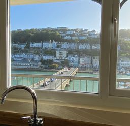 A kitchen with a view of a bridge and houses at Rivercrest in Looe