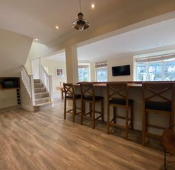A kitchen with bar stools and staircase at Nesden House