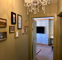 A hallway with framed pictures and a chandelier at Downton II in Alnwick