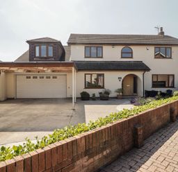 A house with a garage and driveway at Ty Traeth in Porthcawl