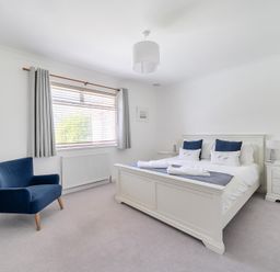 A bedroom with a bed and blue chair at Sleeps 9 KingBeds Family Friendly in Pityme near Penmayne