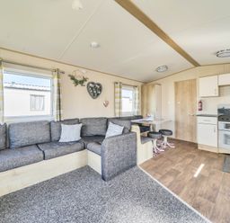 A living room with a sofa and kitchen unit at Sleeps 8 Communal Spa Access Parking Rhyl