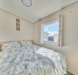 A bedroom with a bed and window at Sleeps 8 Communal Spa Access Parking Rhyl