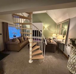 A living room with a spiral staircase and a television at 2 Bed Cottage Sleeps 4 Parking Wifi Darnick
