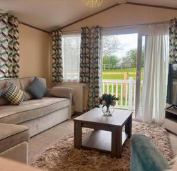A living room with a sofa and coffee table at Caravan in Holcot Sleeps 6 Max 6 people Max 4 adults per booking Pet Friendly Holcot near Moulton