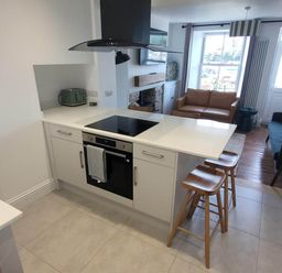 A kitchen with an oven and bar stools at Looe Cottage Seaside views log fire sleeps 4 in Looe