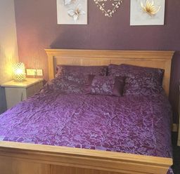 A bedroom with a wooden bed and purple bedding at Fleetwood