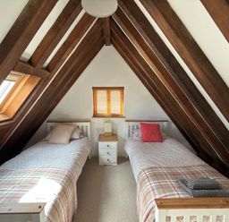 A bedroom with two single beds and wooden beams at Tremail near Camelford