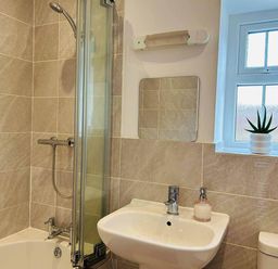 A bathroom with a shower, bathtub, sink, and window at Nebo near Penygroes