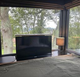 A bedroom with a television and a lamp near a window at The Old Barn in Newton Abbot