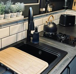 A kitchen with a sink, stove, kettle, and plants at The Old Barn in Newton Abbot
