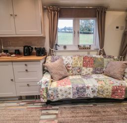 A living room with a sofa and kitchenette at Owls Roost in Robin Hood’s Bay