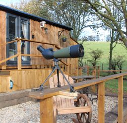 A telescope on a deck in front of a wooden cabin at Owls Roost in Robin Hood’s Bay