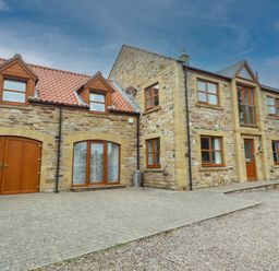 A house exterior with stone walls and a driveway at Alma House in Seahouses