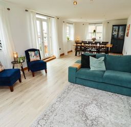 A living room with a sofa and dining table at Alma House in Seahouses