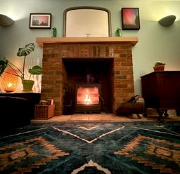 A living room with a fireplace and a rug at Fables Cottage in Otley, Suffolk
