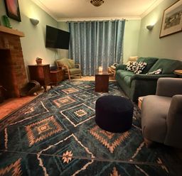 A living room with a sofa, armchair, and fireplace at Fables Cottage in Otley, Suffolk