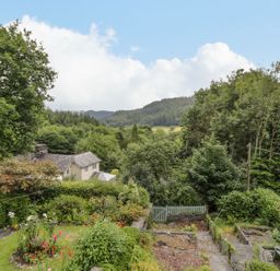 A garden with flowers and trees overlooking mountains at Awelfryn in Betws-y-Coed