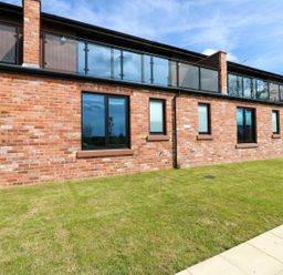 An exterior view of a house with brick wall and balcony at Sycamore Cottage in Frizington