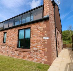 An exterior view of a brick house with a balcony at Silver Birch Cottage in Frizington