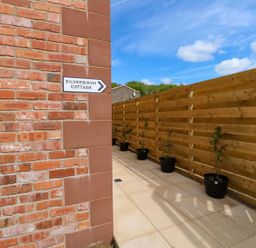 An outdoor pathway with potted plants and a sign at Silver Birch Cottage in Frizington