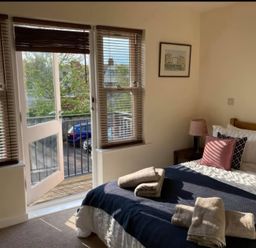 A bedroom with a bed and balcony at Admirals Rest in Weymouth