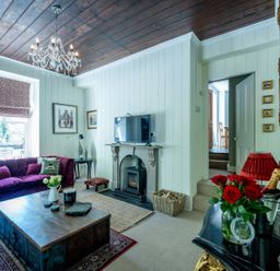 A living room with a television and sofa at Gwynfryn House in Llanbedr