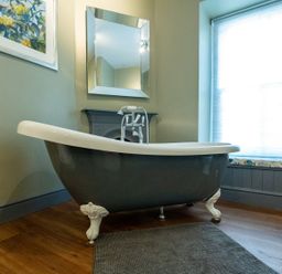 A bathroom with a bathtub and a mirror at Gwynfryn House in Llanbedr