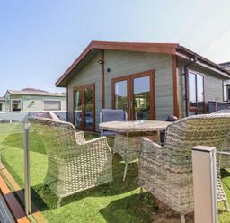 An outdoor seating area with a table and chairs at Excalabur 10 in Morfa Bychan