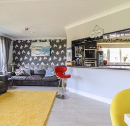 A living room with a sofa and a bar stool at Excalabur 10 in Morfa Bychan