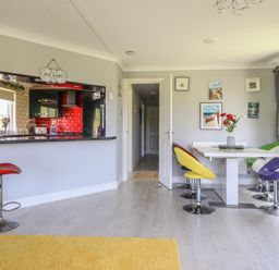 A dining room with a bar counter and colorful chairs at Excalabur 10 in Morfa Bychan