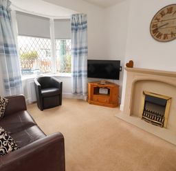 A living room with a sofa and television at 19 Dunstan View in Seahouses
