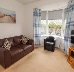 A living room with a sofa and television at 19 Dunstan View in Seahouses