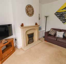 A living room with a fireplace and sofa at 19 Dunstan View in Seahouses