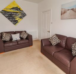 A living room with two sofas and wall art at 19 Dunstan View Seahouses