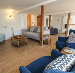 A living room with sofas, armchairs and a coffee table at Greenwich Cottage in Burton Bradstock