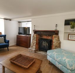 A living room with a fireplace and television at Greenwich Cottage in Burton Bradstock