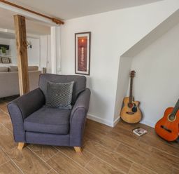 A living room with an armchair and guitars at Greenwich Cottage in Burton Bradstock