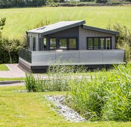 A house with patio and surrounding grass at Hideaway Lodge Llanfechell