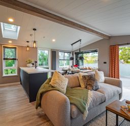 A living room with a sofa and kitchen island at Hideaway Lodge in Llanfechell