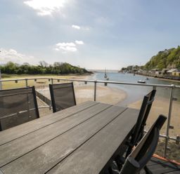 An outdoor space with a table and chairs overlooking a waterway at Seafarer's Haven in Porthmadog