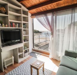 A living room with a television and a bookshelf at Seafarer's Haven in Porthmadog
