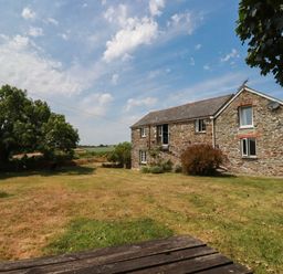 A house with windows and a door surrounded by grass and trees at The Granary